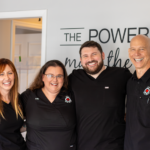 Atlas Total Health staff of three standing in the lobby, all smiling