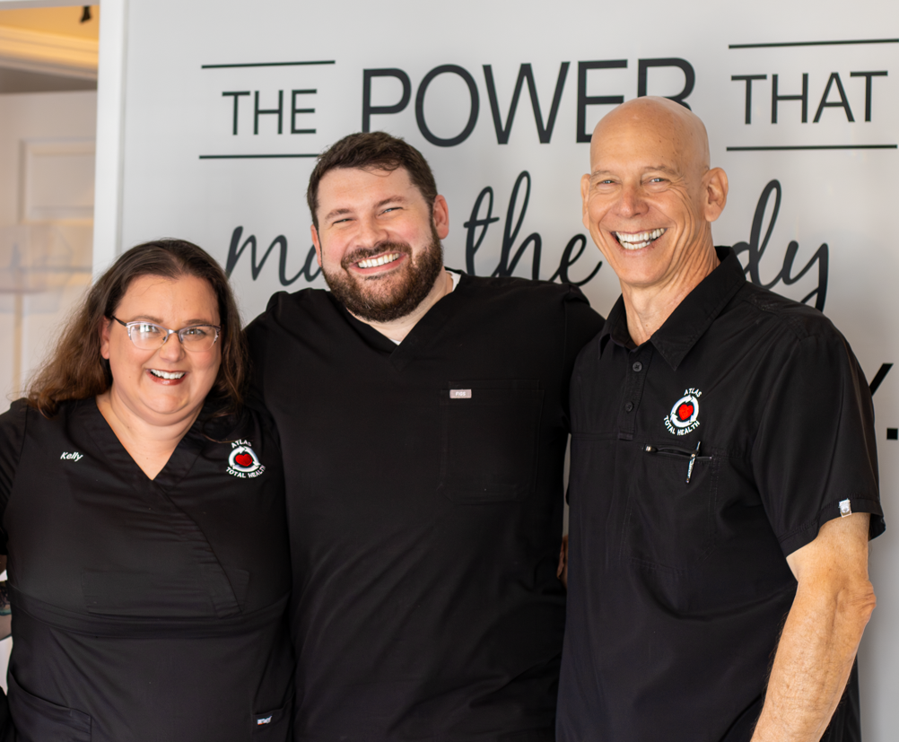 Atlas Total Health staff of four standing in the lobby, all smiling