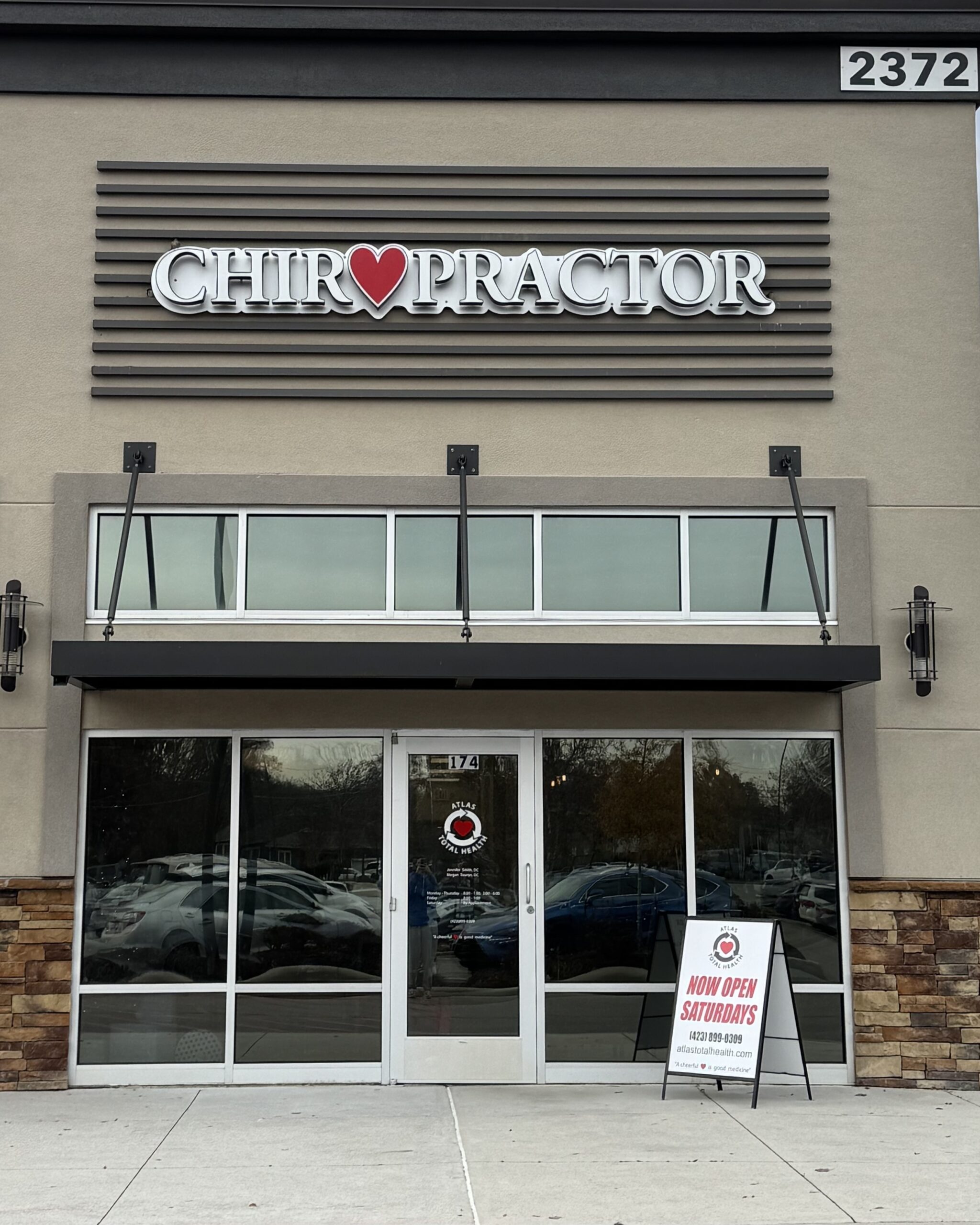 Front of Shallowford office location with "Chiropractor" above the door and a sign up front reading, "Now Open Saturdays"