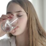 Young white woman with long dirty blond hair drinking a glass of water