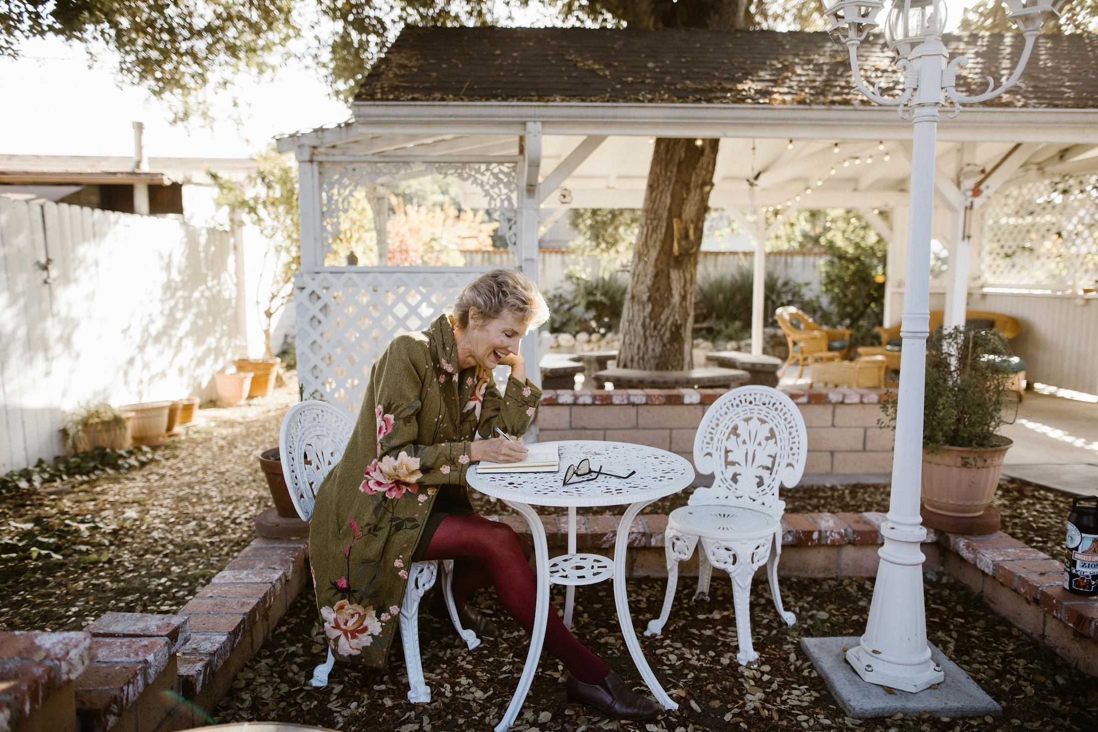 older woman writing in journal outside